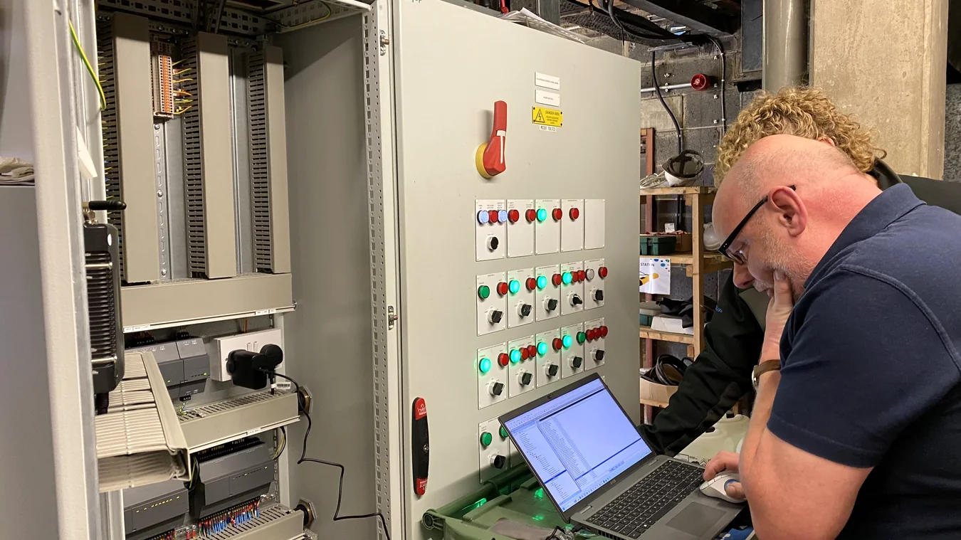 Engineer reviewing an industrial control panel with a laptop